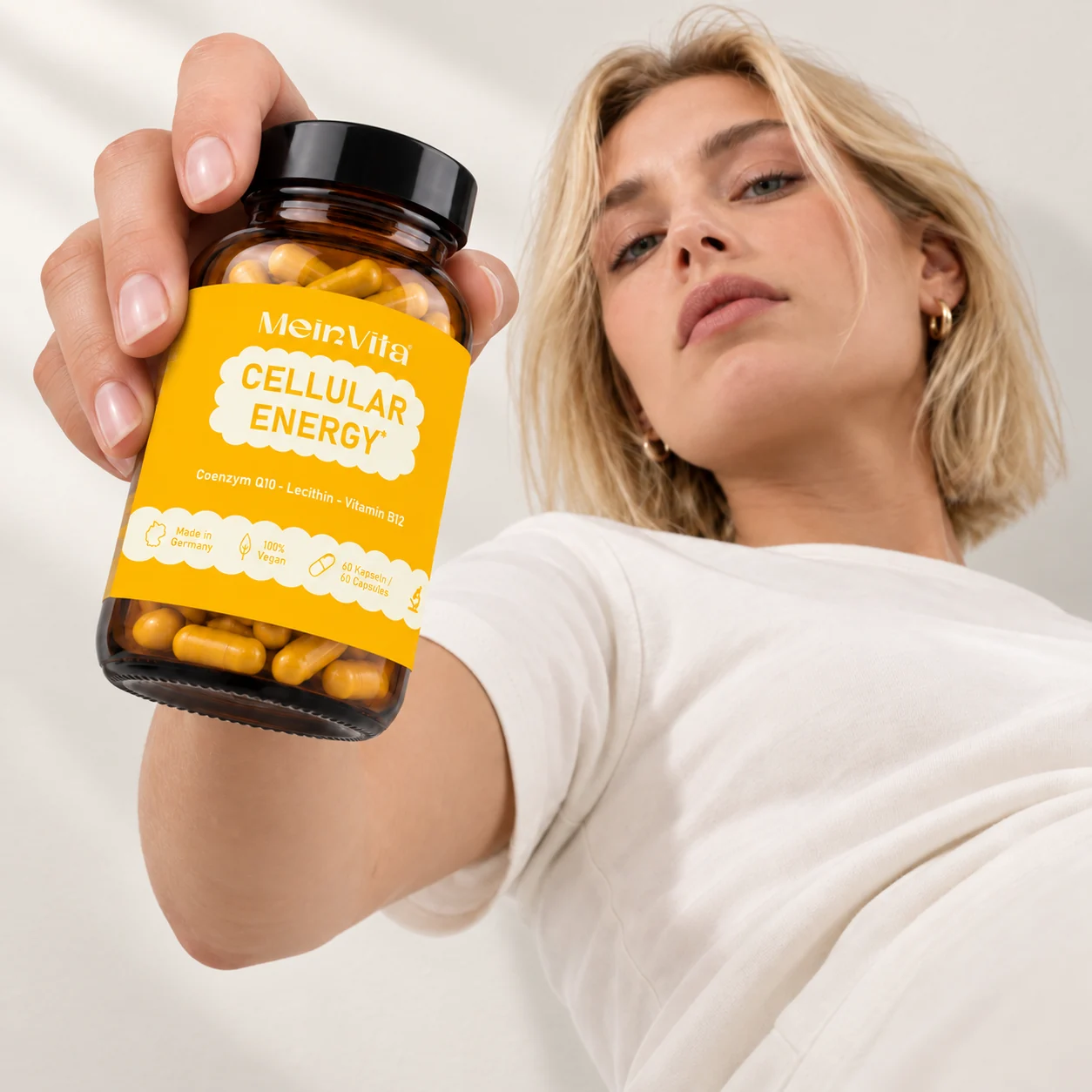 Frau hält ein Glas mit MeinVita Cellular Energy in die Kamera